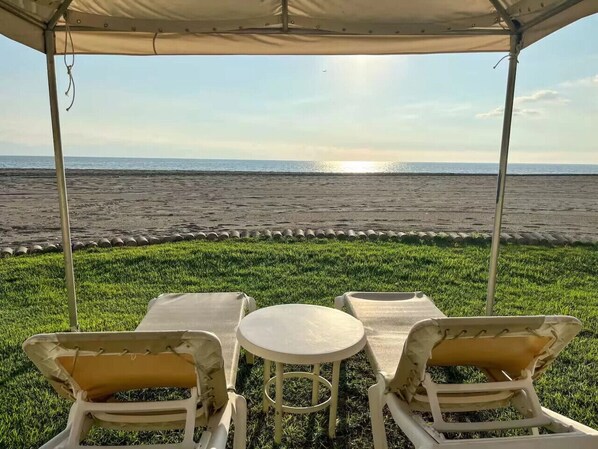 A covered outdoor seating area with a view of the beach and ocean. - Beachfront Penthouse stunning views (Puerto Vallarta)