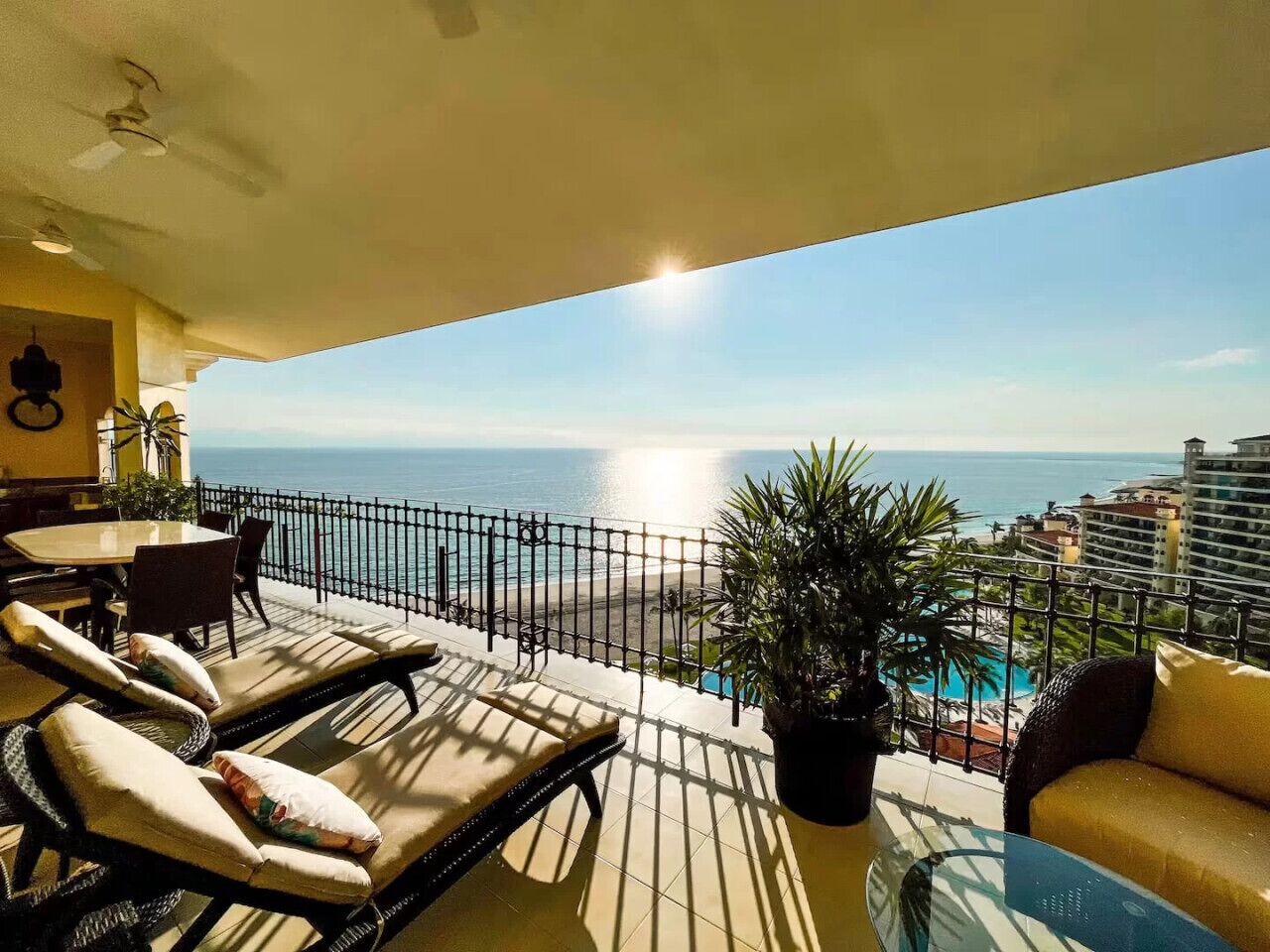 A balcony with sun loungers, a table, and a potted plant.
