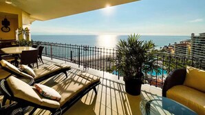 Un balcon avec des chaises longues, une table et un pot de fleurs.