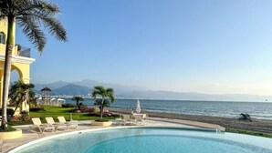 Une piscine offrant une vue dégagée sur la mer et les montagnes en arrière-plan.