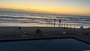 Blick auf einen Strand mit Poolbereich, inklusive einer Umzäunung, Bänken und einem Rettungsschwimmerstand.