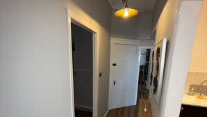 A hallway with wooden flooring, white walls, and a ceiling light fixture. - Ayr Town Centre Apartment - 3 Bedrooms (Ayr)