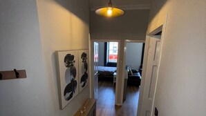 A hallway with a radiator, a hanging light fixture, and a door leading to another room. - Ayr Town Centre Apartment - 3 Bedrooms (Ayr)
