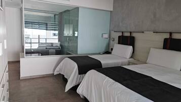 Habitación de hotel con dos camas, un espejo grande y vista al exterior.