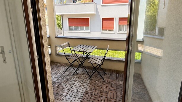 A view of a balcony with a table and chairs, a tiled floor, and a building with red shutters in the background. - Fantastic studio in the city centre (Art 8) (Zürich)