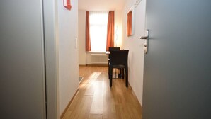 A hallway with a wooden floor, a radiator, and a chair in the distance.