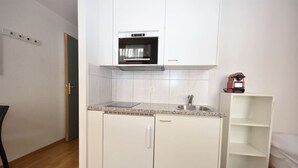 A compact kitchen with a built-in oven, a sink, and a small cabinet.