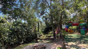 A playground with a slide, swings, and a fire pit area. - Nature, swimming pool, billiards, barbecue and comfort – Quinta do Remanso (Mairiporã)