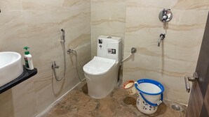 A bathroom with a toilet, a sink, a shower, and a bidet. - DM PAYING GUEST HOUSE (VARANASI)