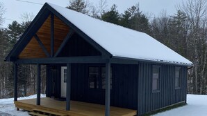 A wooden cabin with a covered porch and a snow-covered roof.