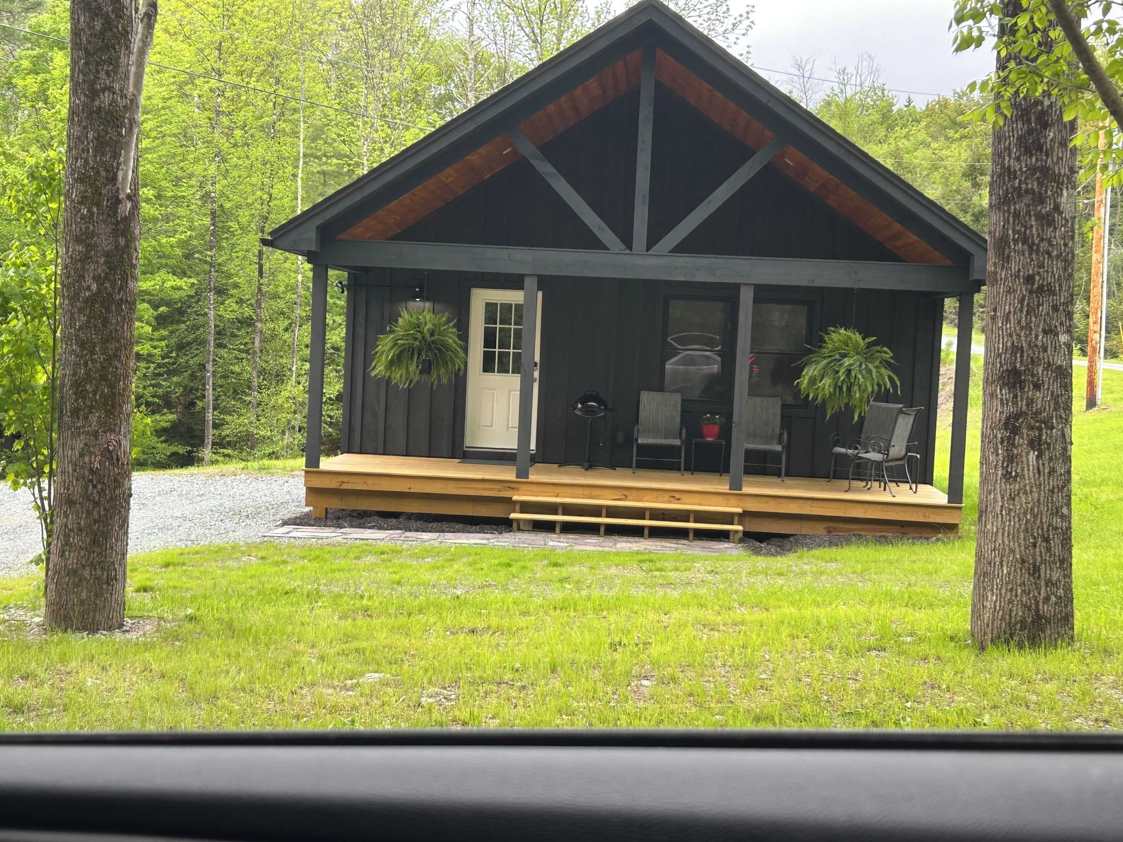 Eine Holzhütte mit einer Holzterrasse, einer Tür und zwei Blumentöpfen.