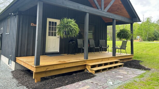 A rustic cabin with a wooden porch, a door, and a large potted plant.