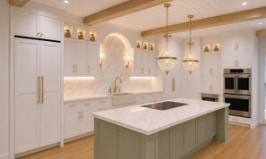 A modern kitchen with white cabinetry, a marble island, and pendant lighting. - Ocean Club 4405: Luxe Oceanfront Escape with Captivating Views! (Isle of Palms)