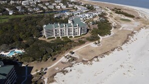 Hotel com vários andares, piscina, próximo à praia e rodeado por vegetação.