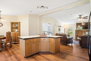 Une cuisine spacieuse dotée d’un grand îlot central, de meubles en bois et d’un coin repas avec une table et des chaises.
