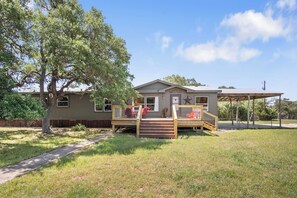 A single-story house with a porch, a fenced deck, and a covered outdoor area.