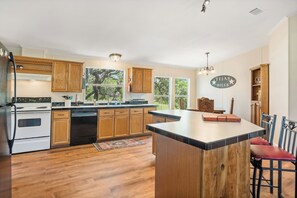 A kitchen with wooden cabinets, a central island, and a view of the outdoors.