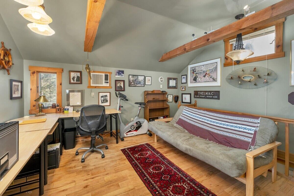 Une pièce confortable avec un bureau, un fauteuil de bureau, un vélo d’exercice et un canapé agrémenté d’un plaid à motifs.