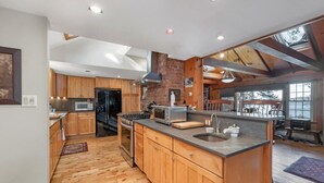 A spacious kitchen with wooden cabinets, a large island, and a view of the outdoors. - Chestnut Cove Cottage- Winnipesaukee - Alton (Alton)