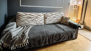 En moderne stue med en mørk sofa, mønstrede puder og et tæppe med et fisbenmønster.