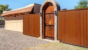 Un edificio con puerta de madera marrón, reja metálica y techo de tejas.