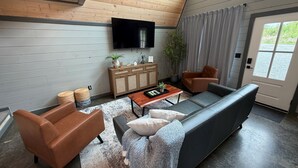 A modern living room with a sofa, armchairs, a coffee table, a television, and a cabinet.