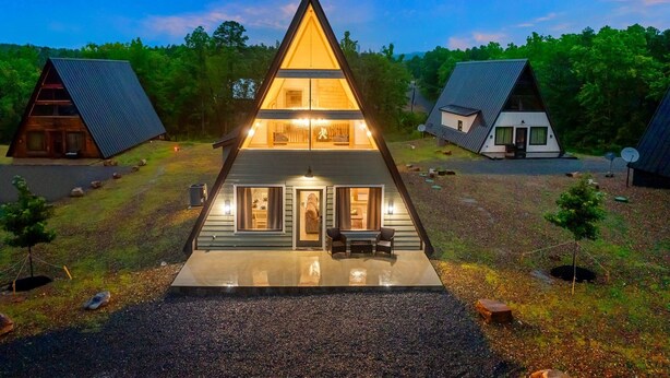 A modern, triangular-shaped house with a central entrance and two smaller structures on either side.