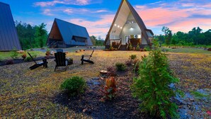 A modern, triangular-roofed building with a spacious outdoor area, including a seating area with chairs and a table.
