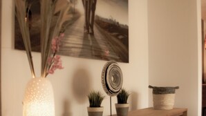A wooden console table with decorative items, a painting, and a vase with flowers.