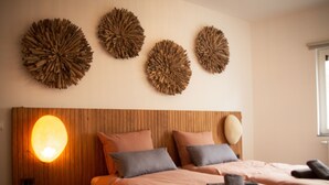 A bedroom with two beds, a wooden headboard, and three wall-mounted decorative pieces.