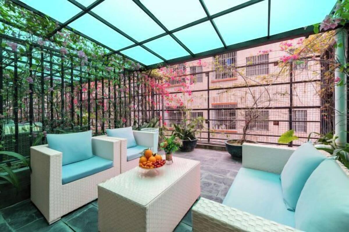 A covered outdoor seating area with wicker furniture and potted plants.