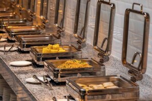 A buffet line with various food options in metal containers, a tiled wall, and a granite countertop. - Fei Li International Hotel (Guangzhou)