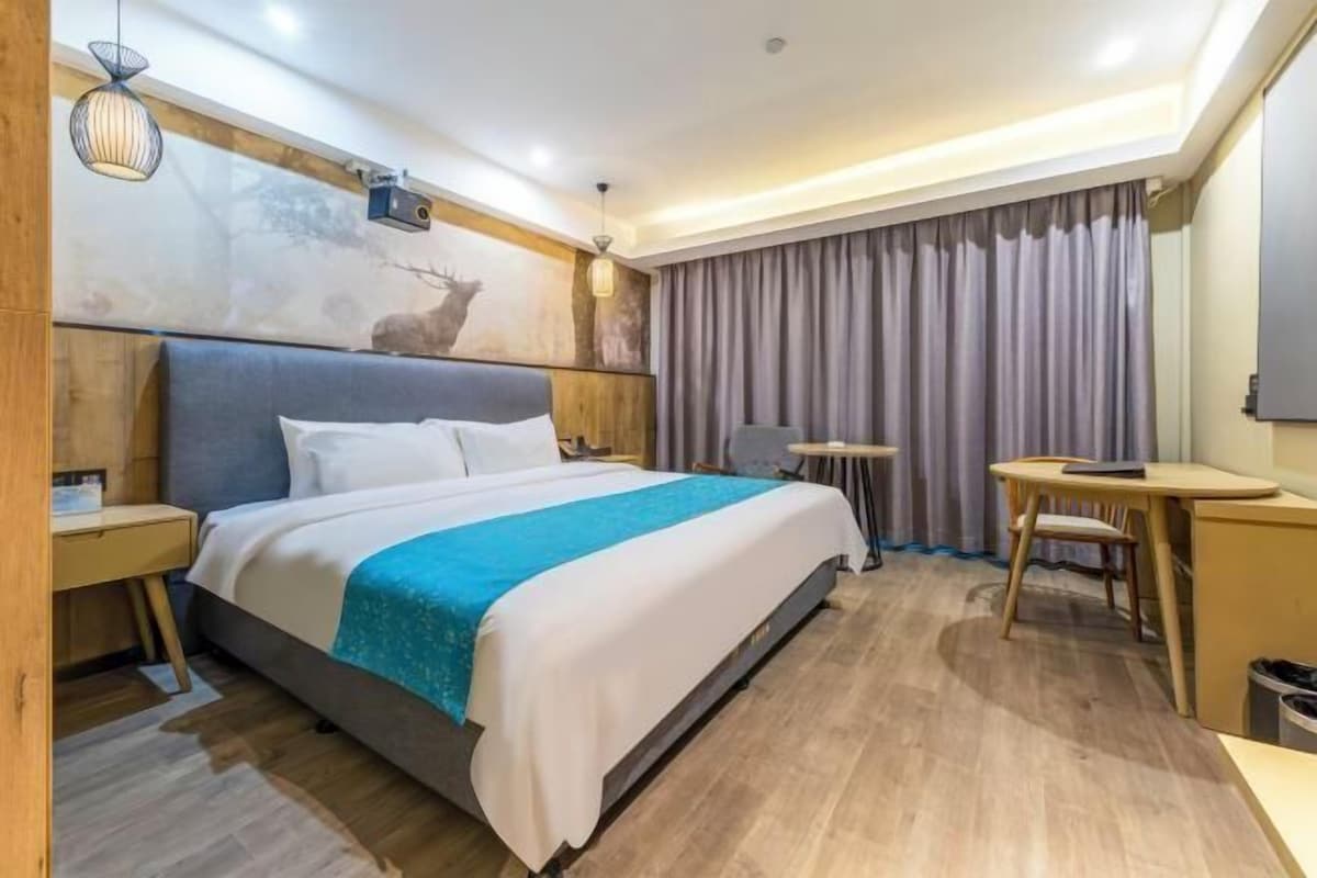 Une chambre d’hôtel moderne, dotée d’un grand lit, d’un bureau et d’une chaise.