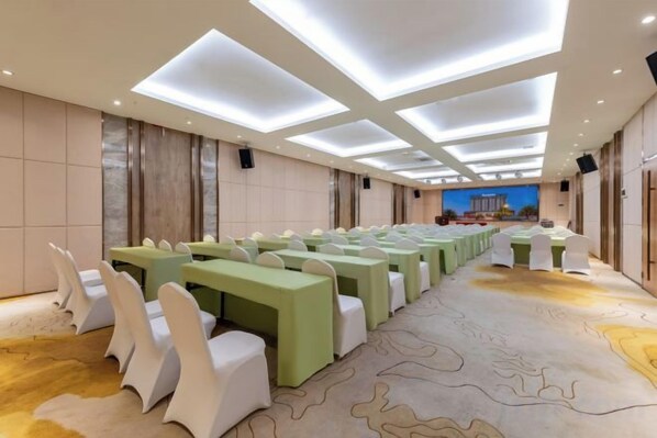 A conference room with rows of tables and chairs, a patterned carpet, and a modern ceiling design.