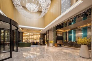 A spacious lobby with a reception desk, seating area, and a large decorative ceiling feature. - Fei Li International Hotel (Guangzhou)