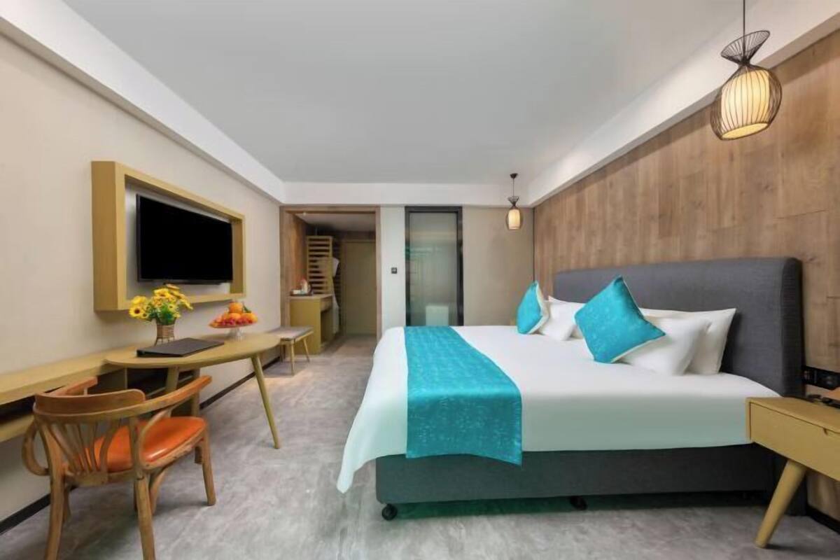 A hotel room with a bed, desk, chair, TV, and a staircase leading to an upper level.