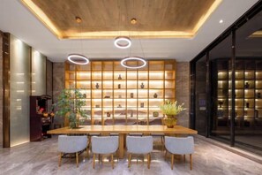 A modern dining area with a wooden table, grey chairs, and a wall of shelves with decorative items. - Fei Li International Hotel (Guangzhou)