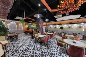 A restaurant interior with multiple seating areas, including round tables and booths, and a patterned floor. - Fei Li International Hotel (Guangzhou)