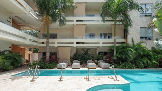 A multi-level hotel with a central swimming pool, outdoor seating, and lush greenery. - Incredible private property: 2 apartments with wifi, pool and nearby cenote (Tulum)