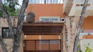 A modern building with a stone facade, a wooden entrance gate, and a balcony with hanging baskets. - Incredible private property: 2 apartments with wifi, pool and nearby cenote (Tulum)