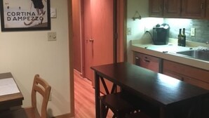 A kitchen with wooden cabinets, a sink, and a countertop. There is a framed picture on the wall and a sign above the door that reads "OUR HAPPY PLACE". - Golf course condo, 10 min to Torch Lake, w/pool, hot tub and sauna! (Mancelona)