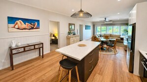 A modern kitchen with a central island, wooden flooring, and a dining area with a sofa and table.