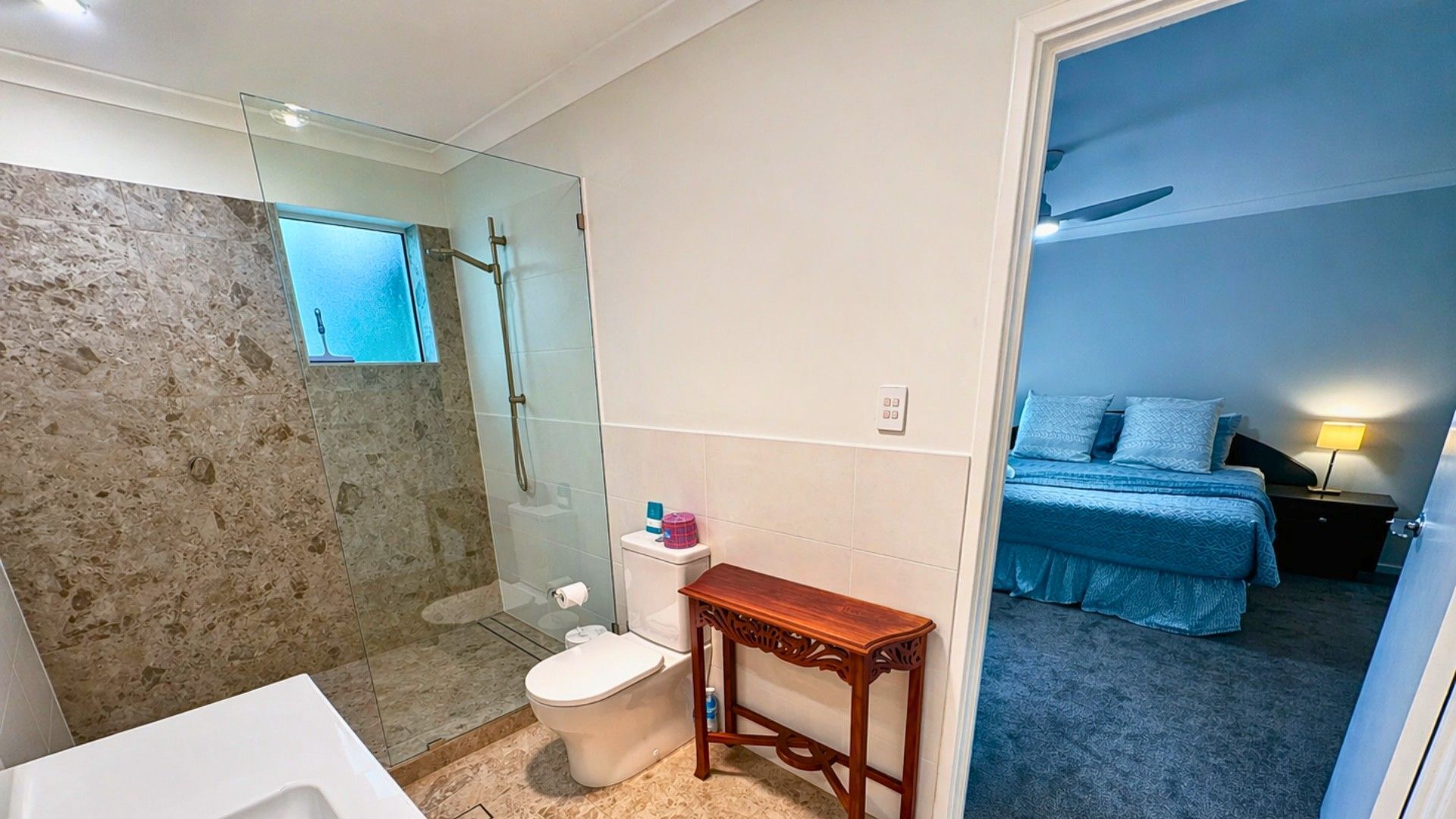 Une salle de bain avec une douche à parois de verre, des toilettes et un lavabo.