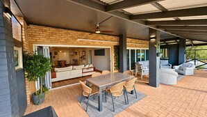 An outdoor patio with a dining table, chairs, and a ceiling fan.