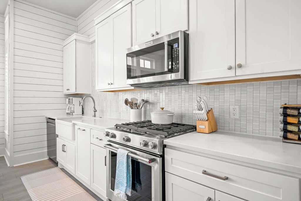 Una cocina moderna con armarios blancos, electrodomésticos de acero inoxidable y salpicadero de azulejos.