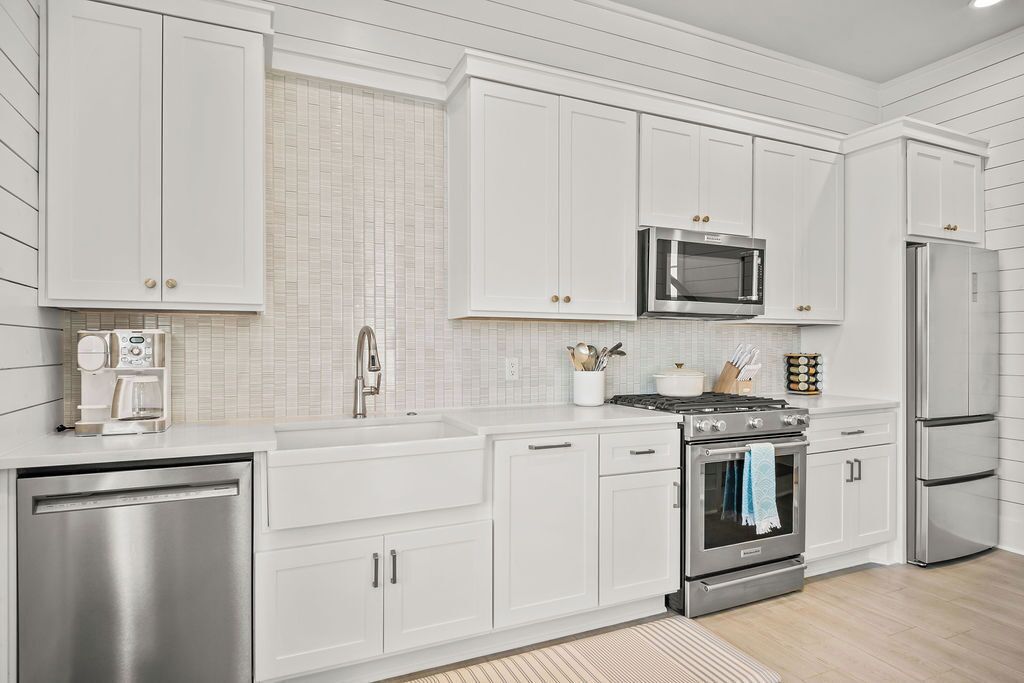 Una cocina moderna con armarios blancos, electrodomésticos de acero inoxidable y un rebozado de azulejos.