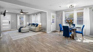 Un vaste espace de vie comprenant un canapé, une table à manger avec des chaises et un ventilateur de plafond.