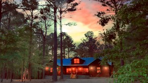 A cabin with a porch, surrounded by trees, during sunset. - Open concept, 4 bd/4bath cabin in the woods, sleeps 12. Great location! (Broken Bow)