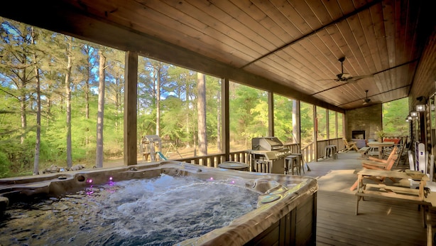 A hot tub in a covered outdoor area with a view of a forest. - Open concept, 4 bd/4bath cabin in the woods, sleeps 12. Great location! (Broken Bow)