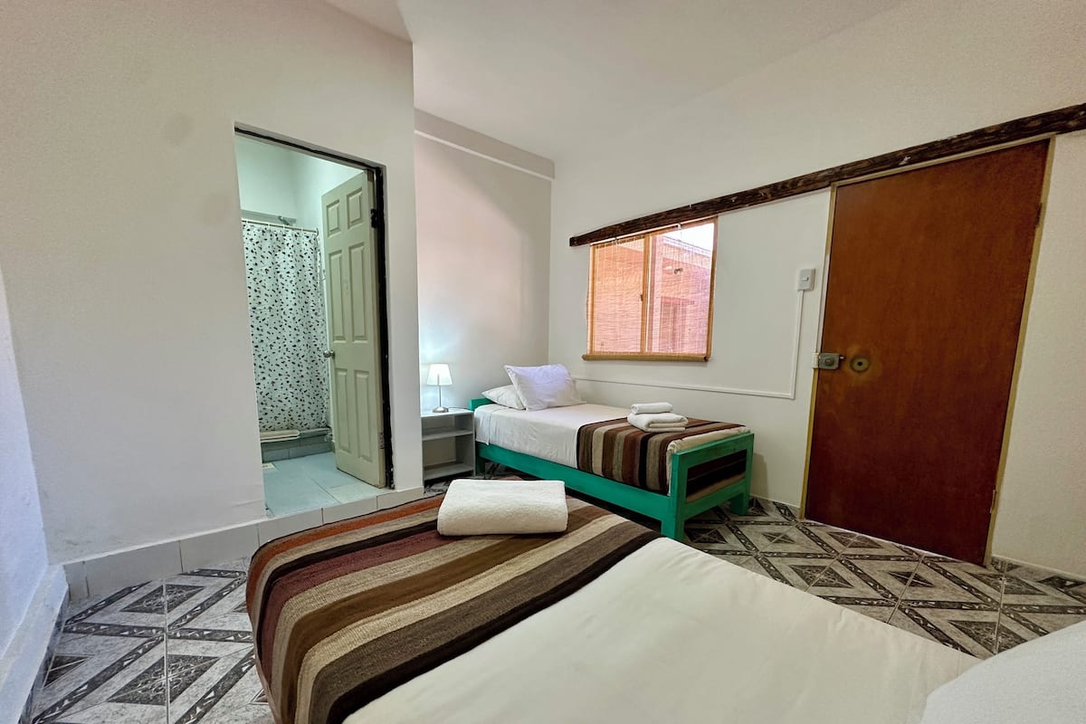 Un dormitorio con una cama, una mesita de noche, una ventana y una puerta.